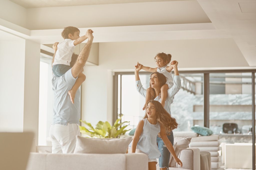 Cheerful parents holding their children on the shoulders