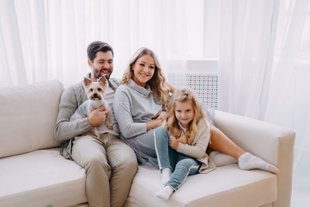 Happy family: mom, dad, daughter and pet. Family in a bright New Year's interior with a Christmas tree.