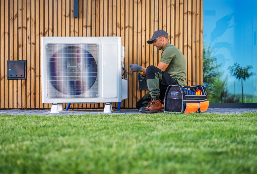 Technician Performing Maintenance on Air Conditioning Unit in Residential Garden During Daytime