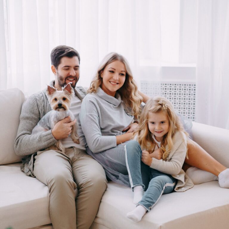 Happy family: mom, dad, daughter and pet. Family in a bright New Year's interior with a Christmas tree.